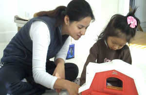 Adult play partner and child playing with toy. 