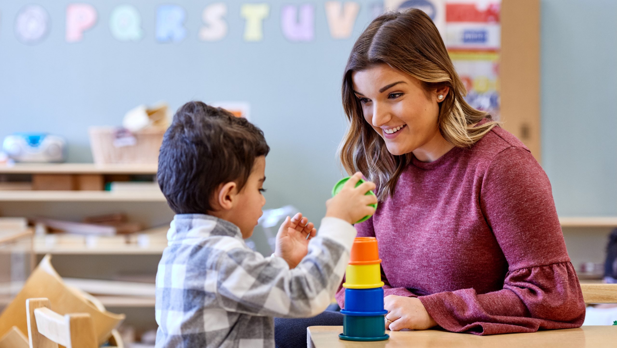 A teacher a child playing with stacking cups.